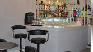 A bar area with a mirrored wall, bar stools, and a variety of bottles and glasses. - Hotel Peppers (Torquay)