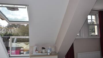 A room with a skylight, a white dresser, a radiator, and a view of buildings outside.