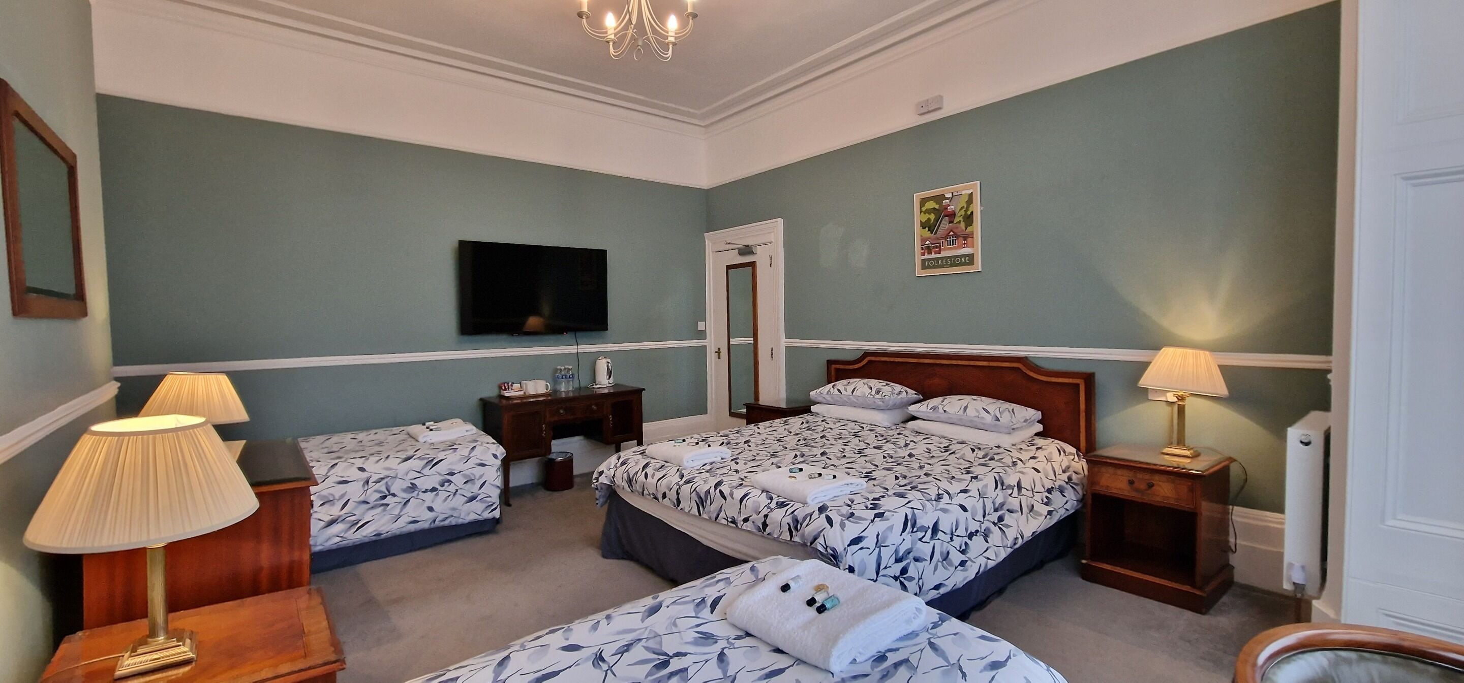 A bedroom with two beds, a TV, a desk, and a lamp.