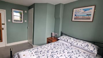 A bedroom with a bed, a nightstand, a framed picture, and a door.