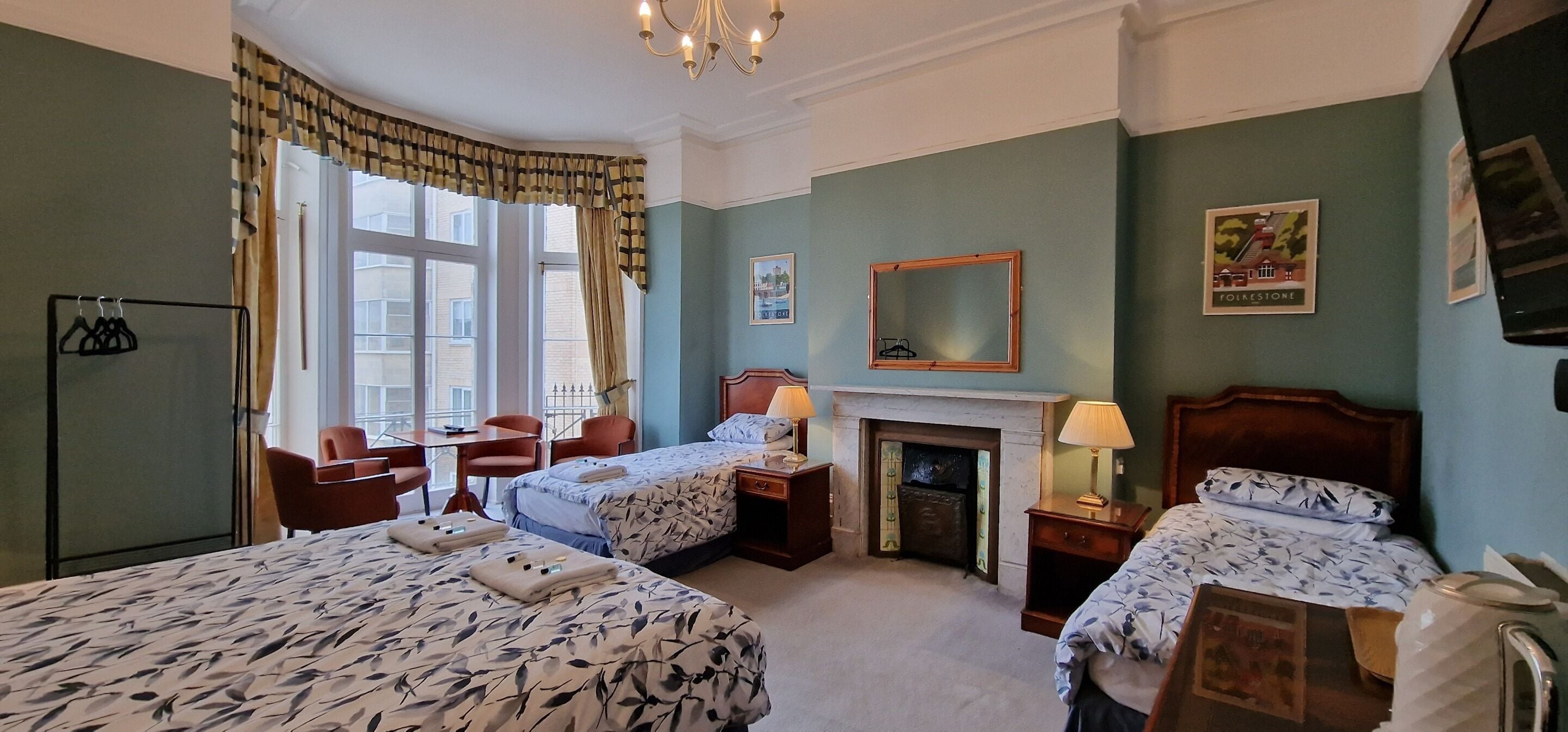Une chambre d’hôtel avec deux lits, une cheminée, un bureau, une chaise et une armoire.