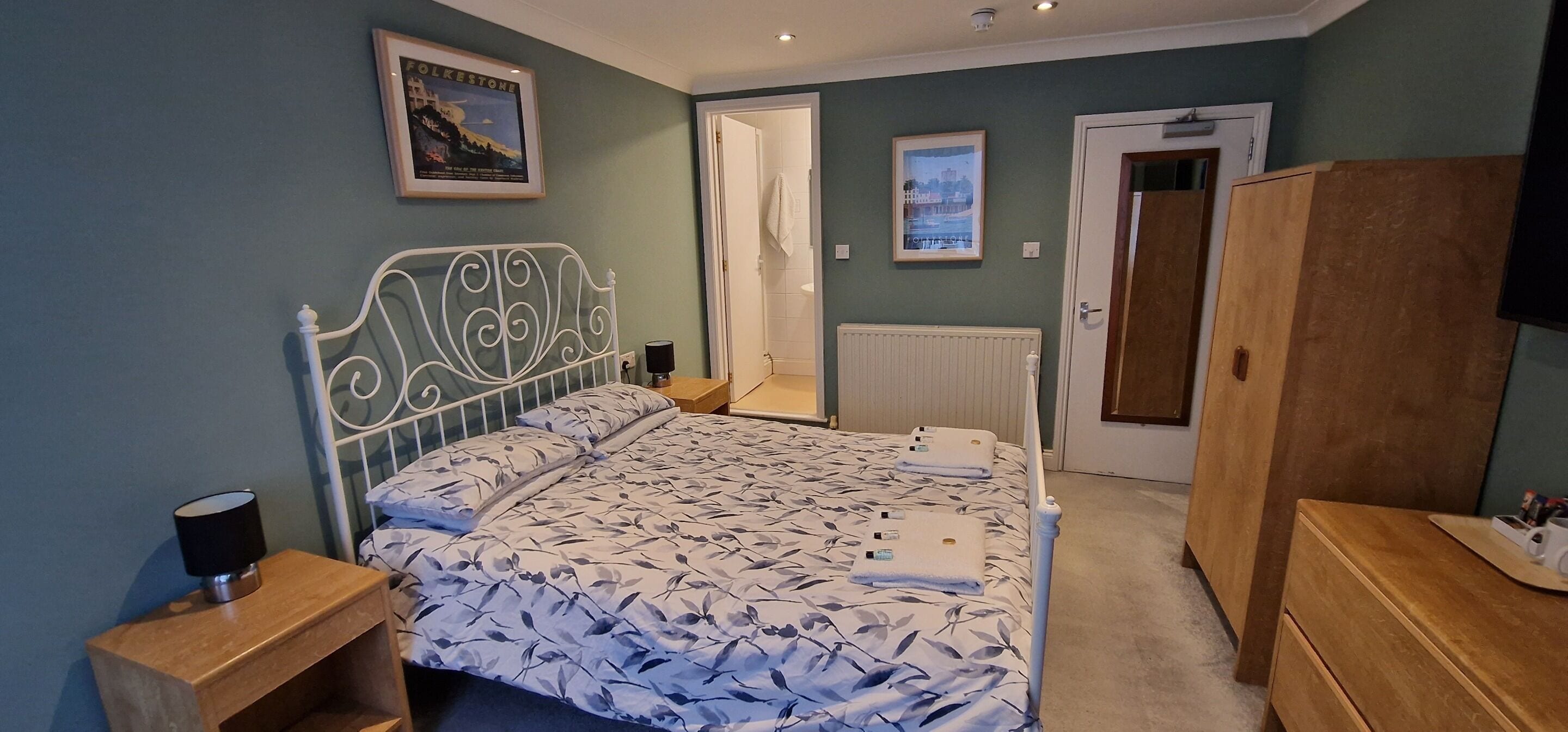 A bedroom with a bed, a wooden nightstand, a wardrobe, and a radiator.
