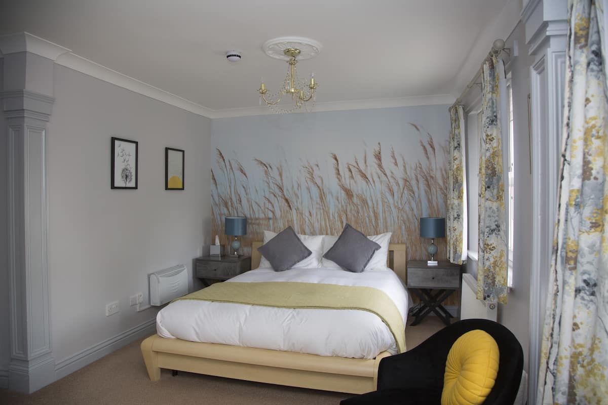 A bedroom with a bed, bedside tables, a chair, and a window with curtains.