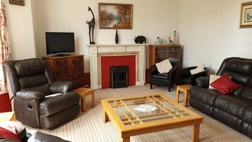 A living room with leather sofas, a fireplace, a television, and a bookshelf.