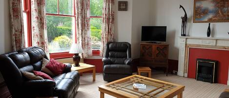 A living room with a leather sofa, a wooden coffee table, a fireplace, and a television.