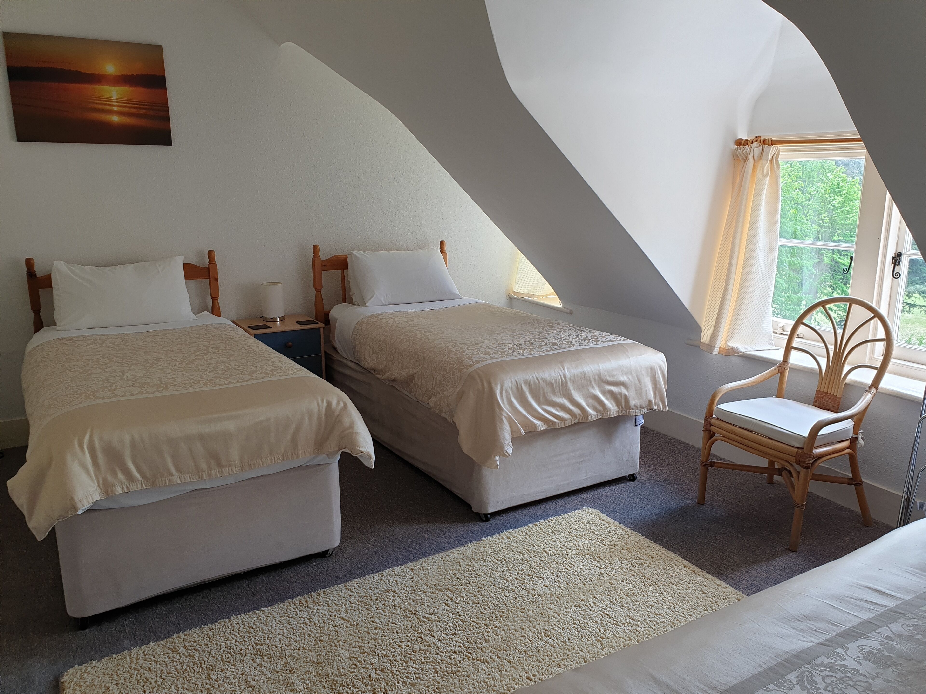 Une chambre avec deux lits, une chaise, une table de chevet et un tableau au mur.