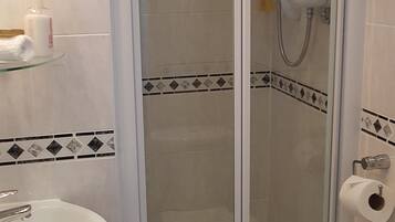 Una ducha con puerta de vidrio, un lavamanos blanco y un inodoro.