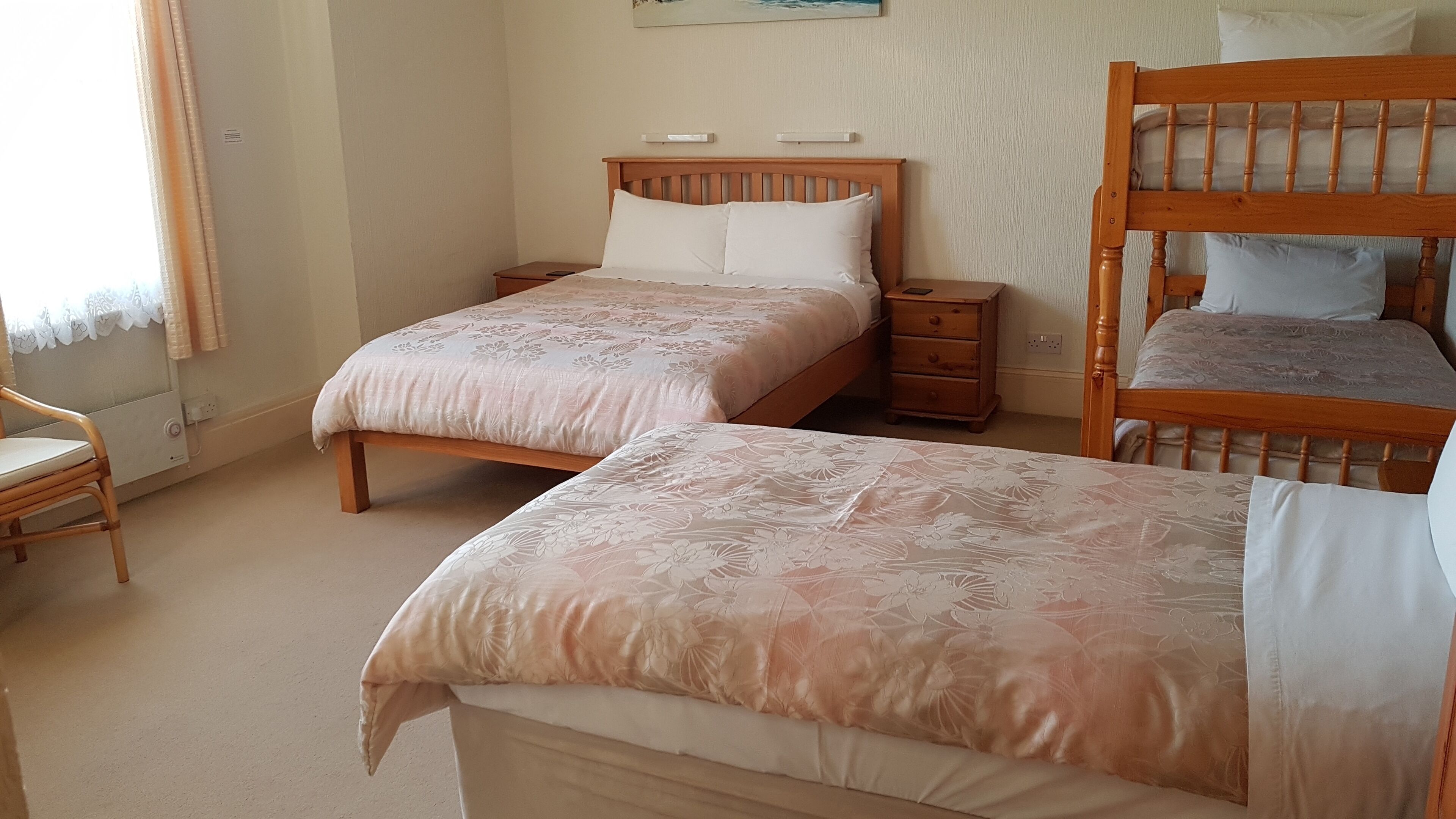 A bedroom with two single beds, a wooden chair, and a nightstand.