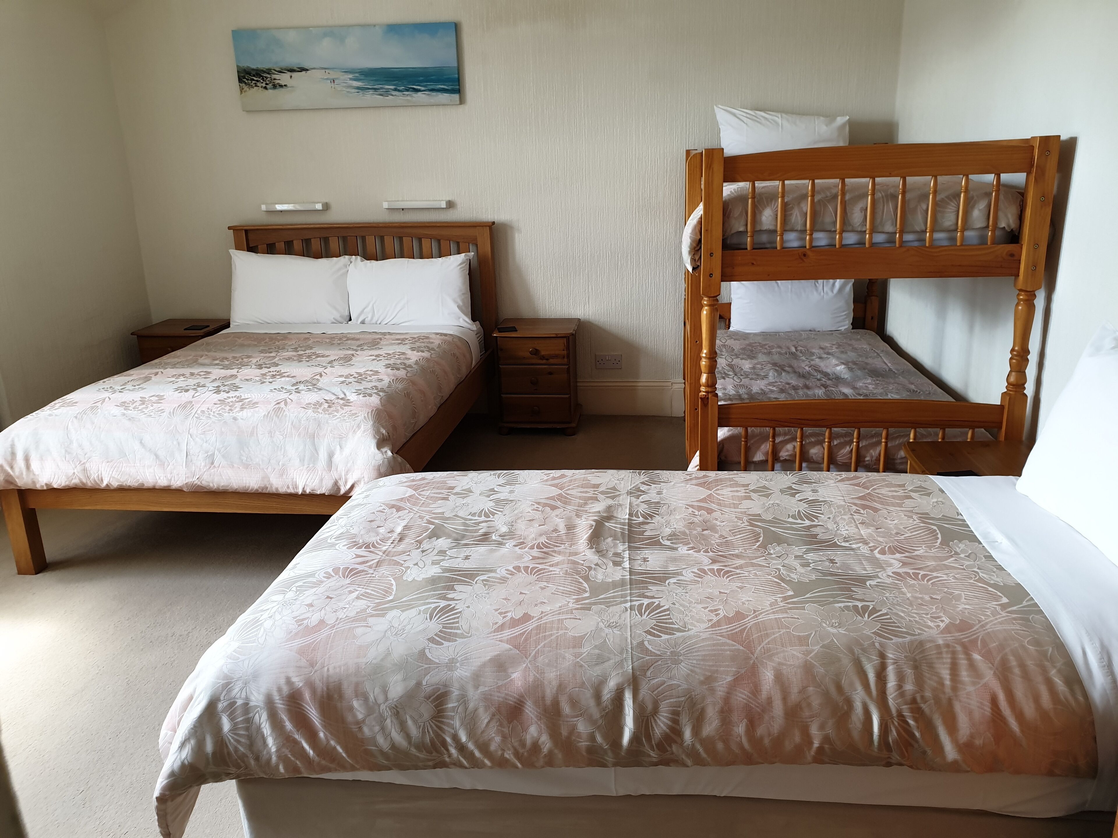 Une chambre avec deux lits simples, une table de chevet et une tête de lit en bois.