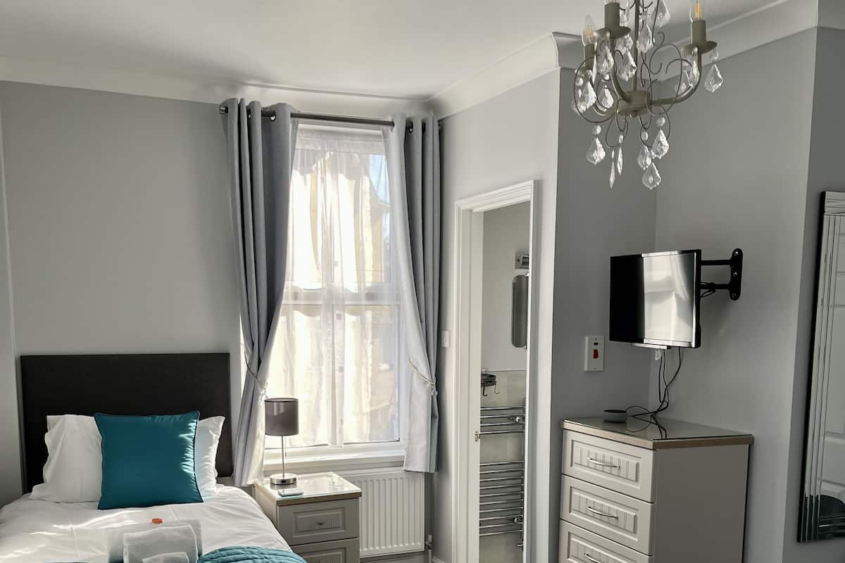 Une chambre d’hôtel avec deux lits, une armoire, un bureau, un miroir et un lustre.