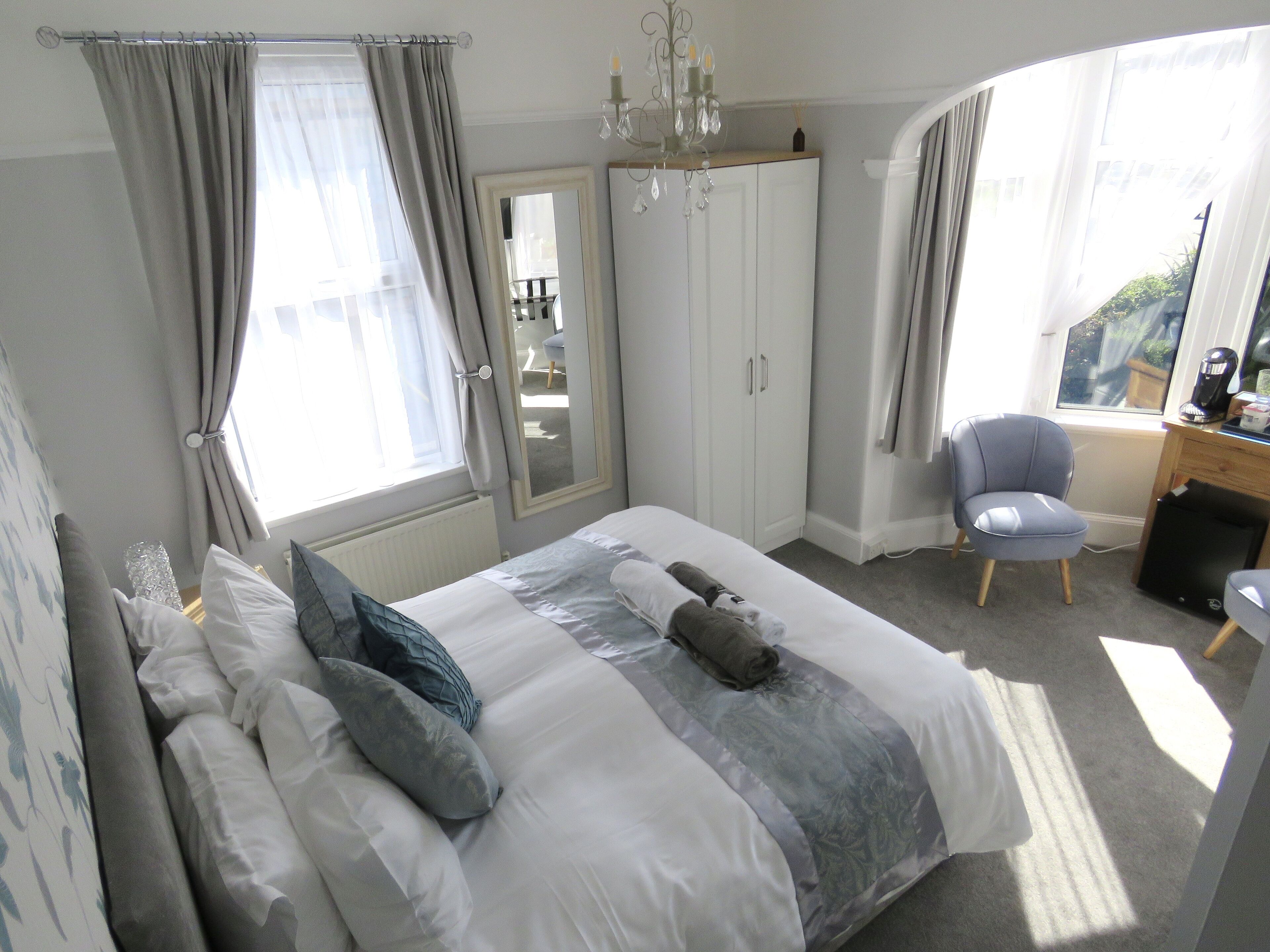A bedroom with a bed, a chair, a desk, and a wardrobe.