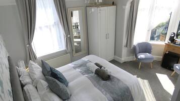 A bedroom with a bed, a chair, a desk, and a wardrobe.