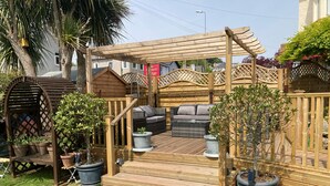 A wooden deck with outdoor furniture, including a sofa and a dining table. - Bentley Lodge Guest House (Torquay)