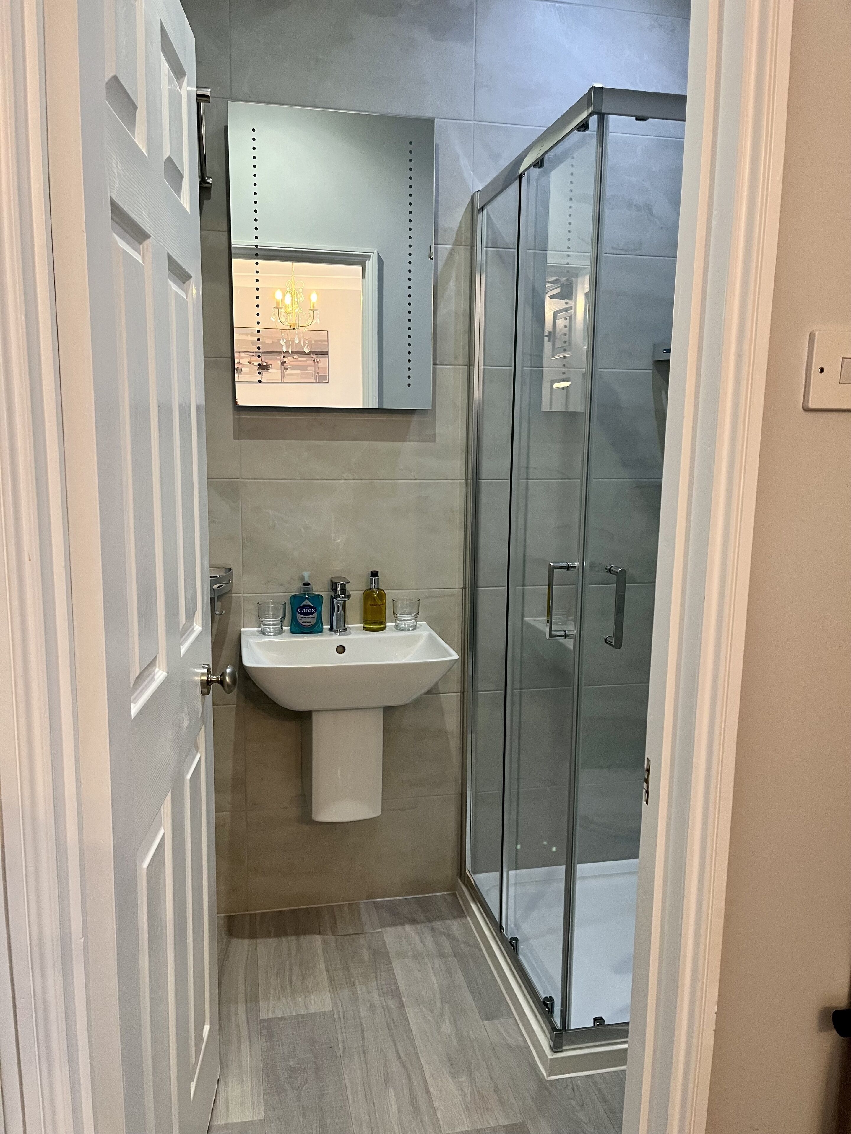 A bathroom with a white sink, a glass shower enclosure, and a mirror above the sink.