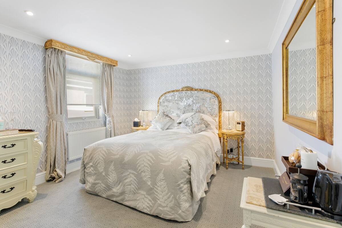 A bedroom with a large bed, a dresser, a nightstand, and a mirror.