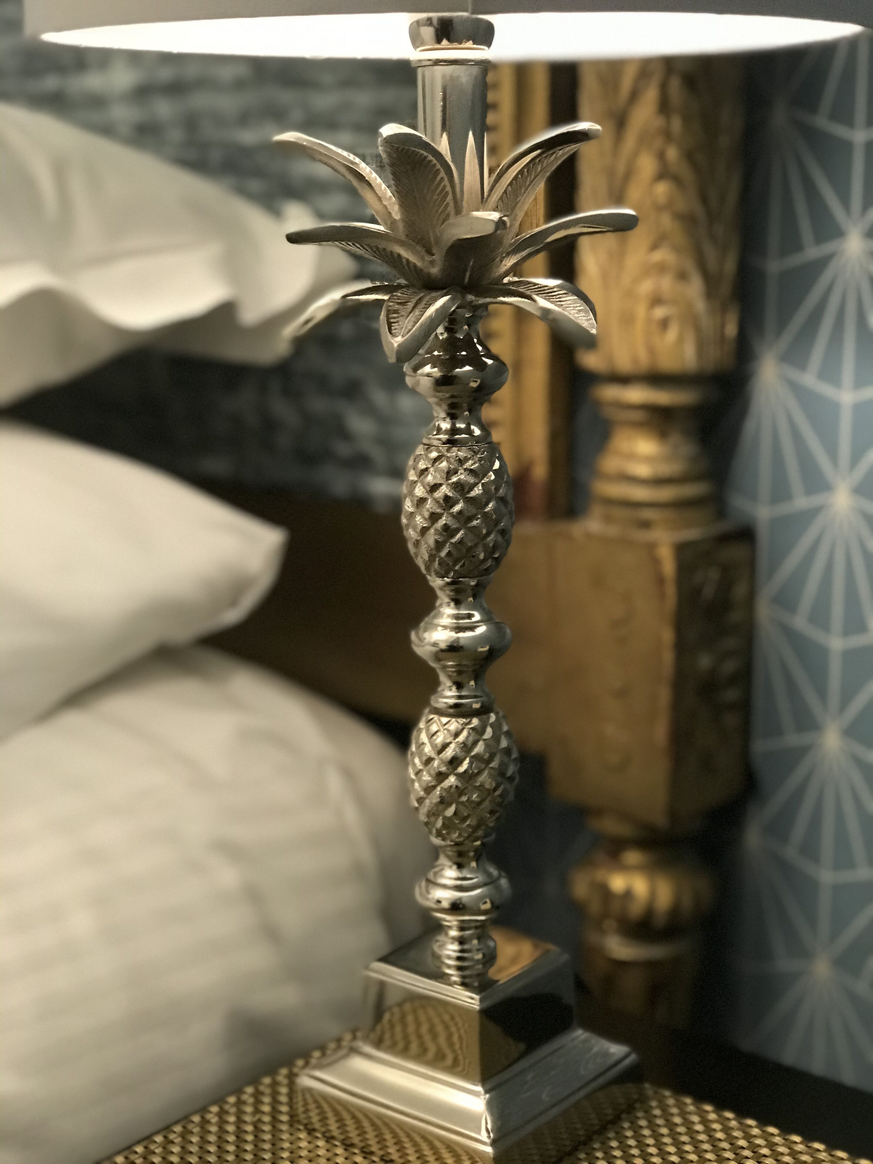 A metallic table lamp with a decorative base and a clear lampshade, placed on a textured surface.