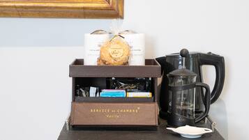 Une petite table avec une machine à café, une boîte étiquetée « SERVICE EN CHAMBRE » et un objet décoratif.