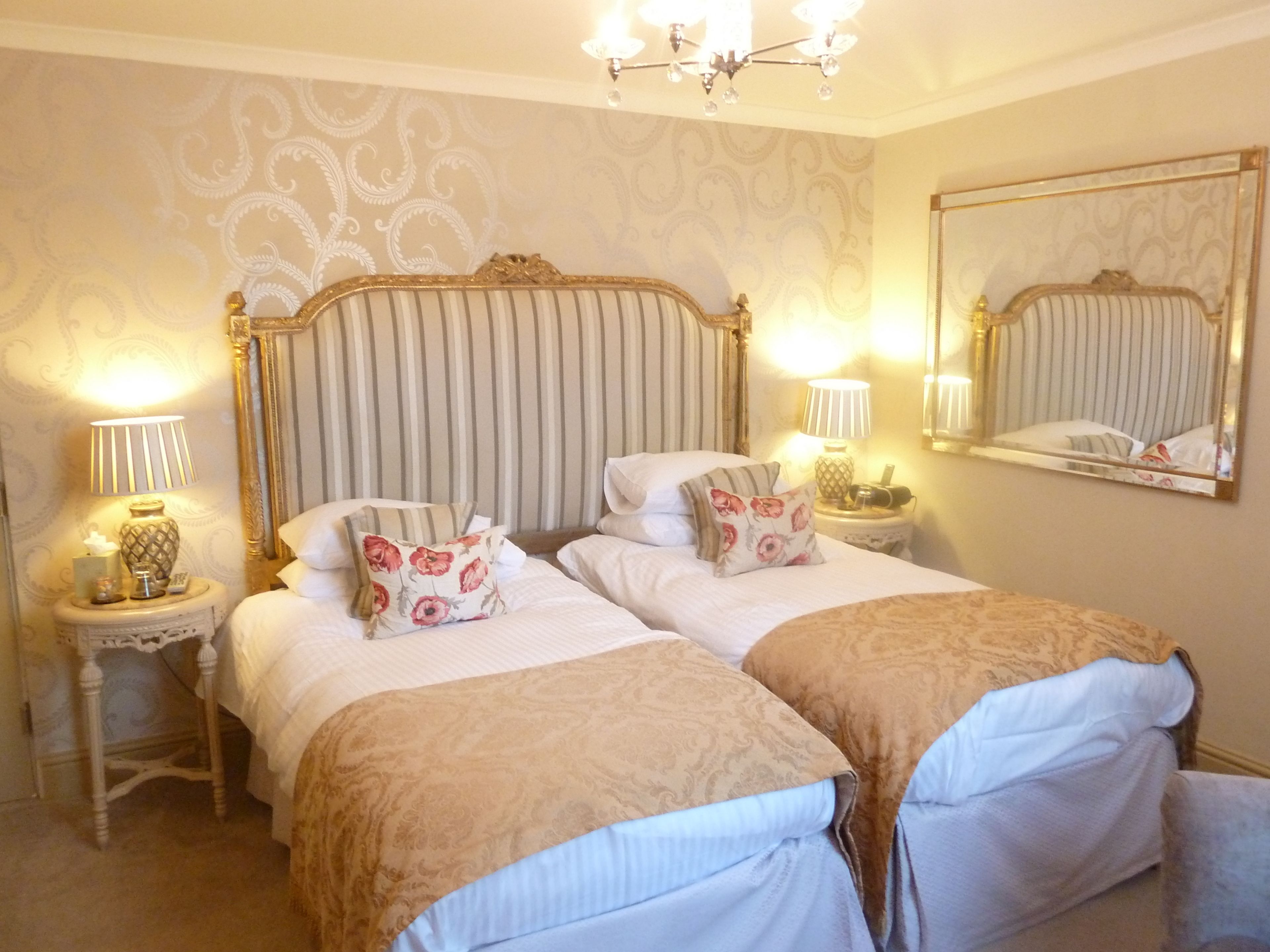A double bed with a striped headboard, two bedside tables with lamps, and a mirror on the wall.