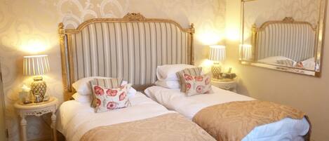 A double bed with a striped headboard, two bedside tables with lamps, and a mirror on the wall.