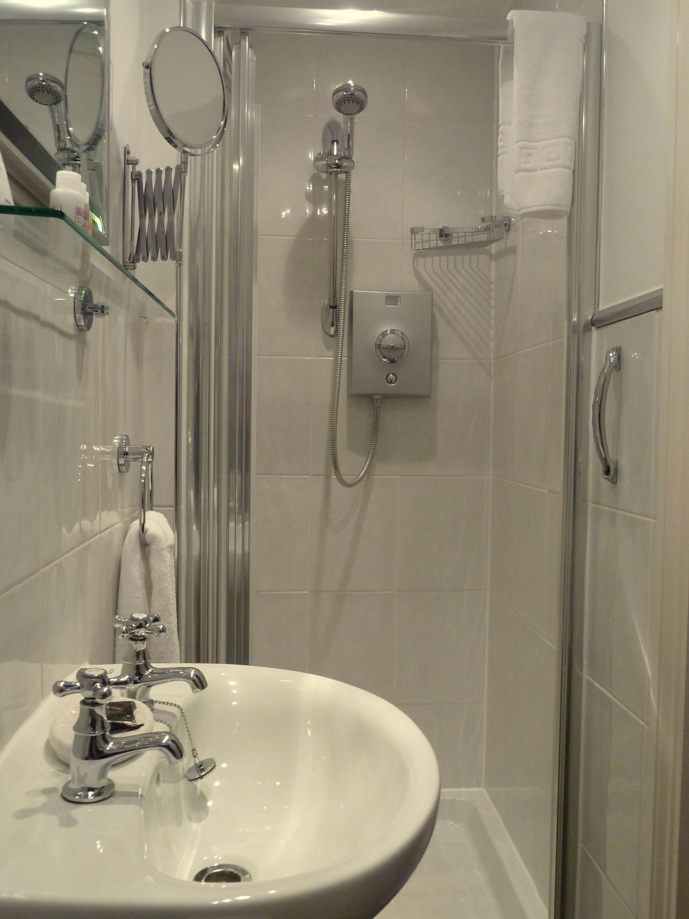 A modern bathroom with a glass shower enclosure, a white sink, and a handheld showerhead.