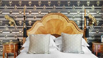 Uma cama com cabeceira de madeira, duas almofadas estampadas e parede decorada.