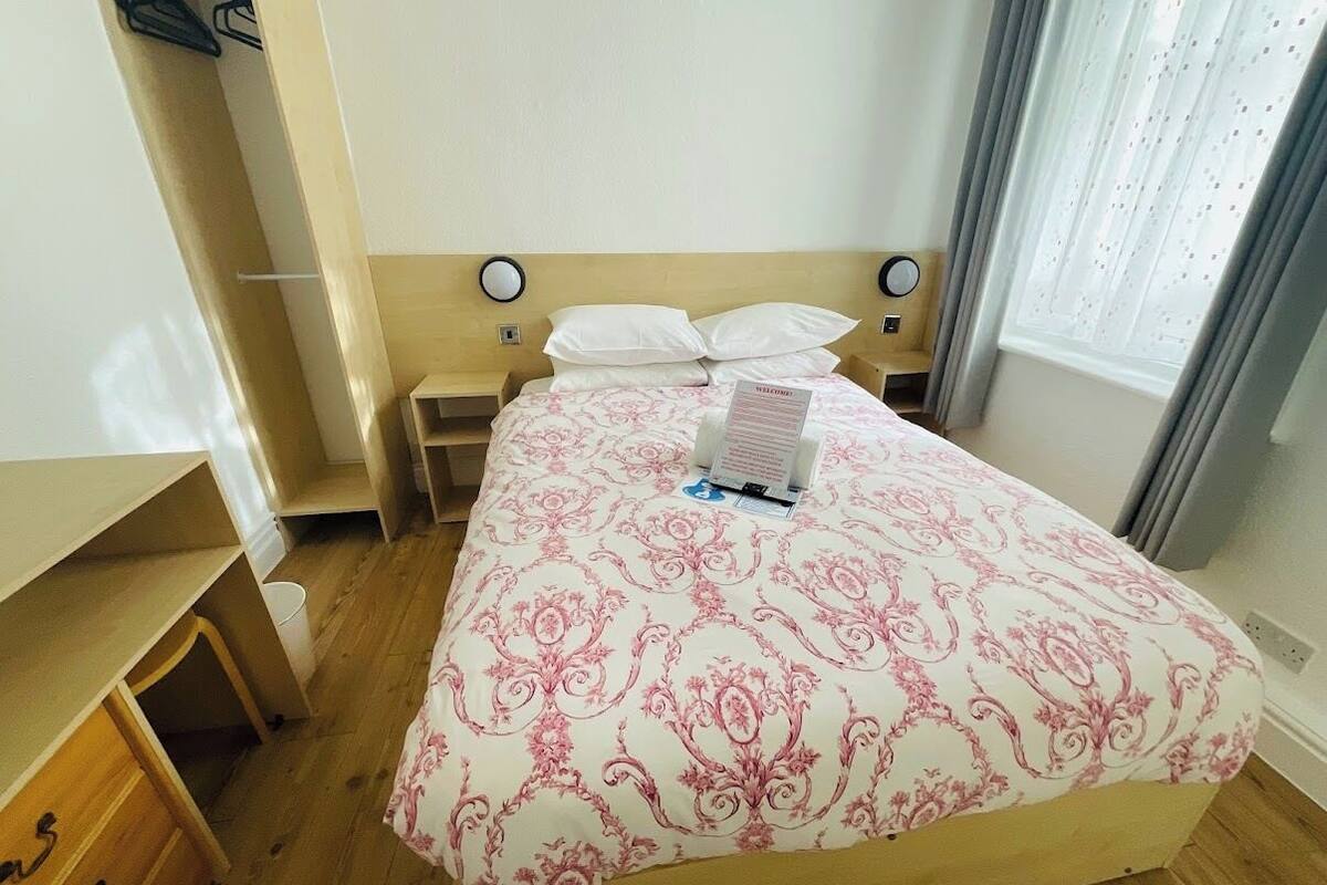 A bedroom with a bed, bedside tables, and a window with curtains.