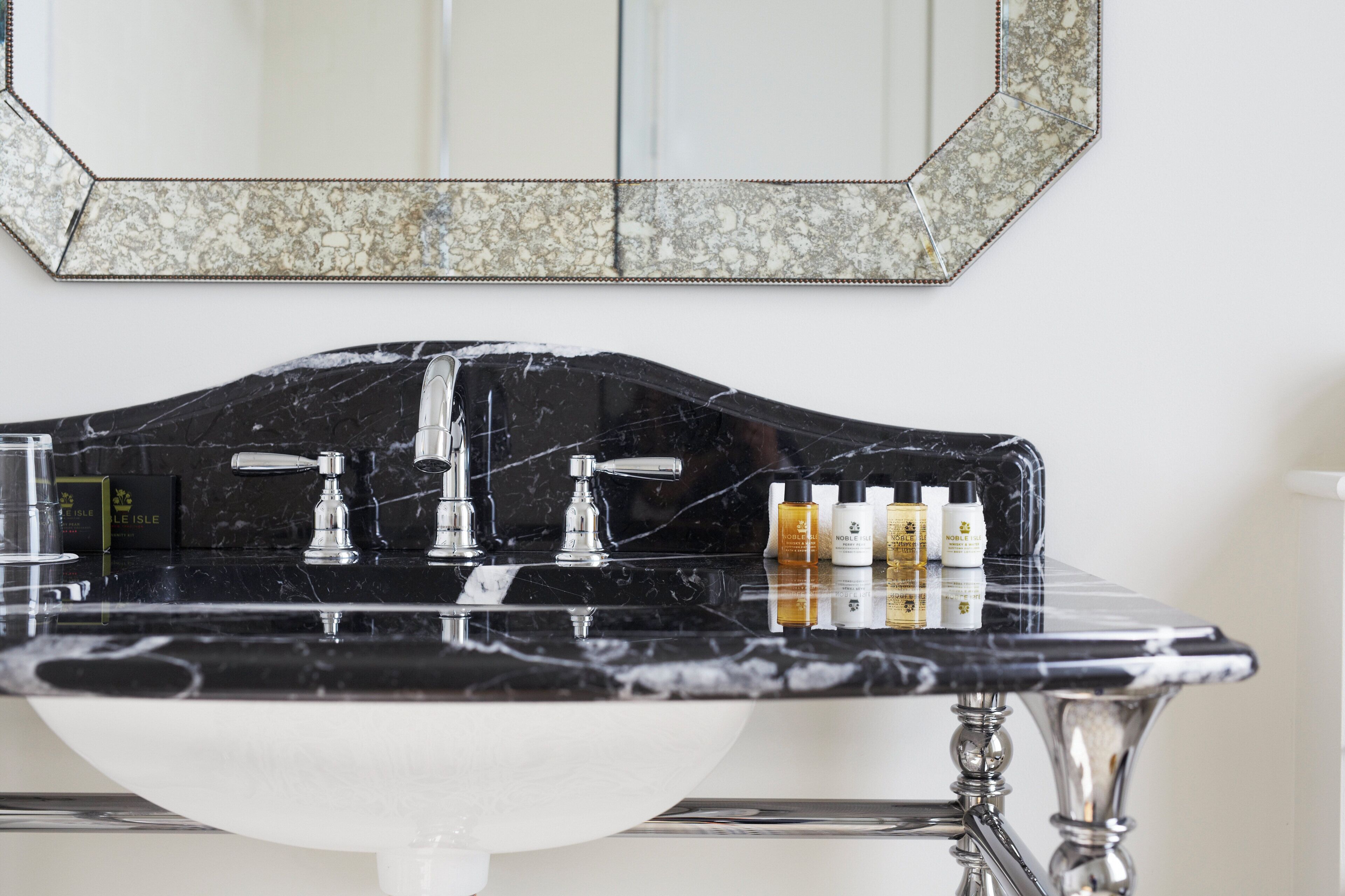 A bathroom with a black marble sink, chrome faucets, and a large mirror.