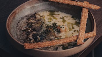 A bowl of soup with breadsticks on a wooden table.