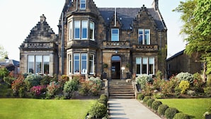 A historic building with a prominent corner turret, large windows, and a well-maintained garden with various shrubs and flowers. - The Roseate Edinburgh (Edinburgh)