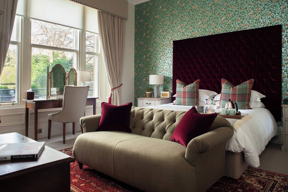 Un dormitorio de hotel con una cama grande, una zona de estar con sofá, un escritorio y una silla.