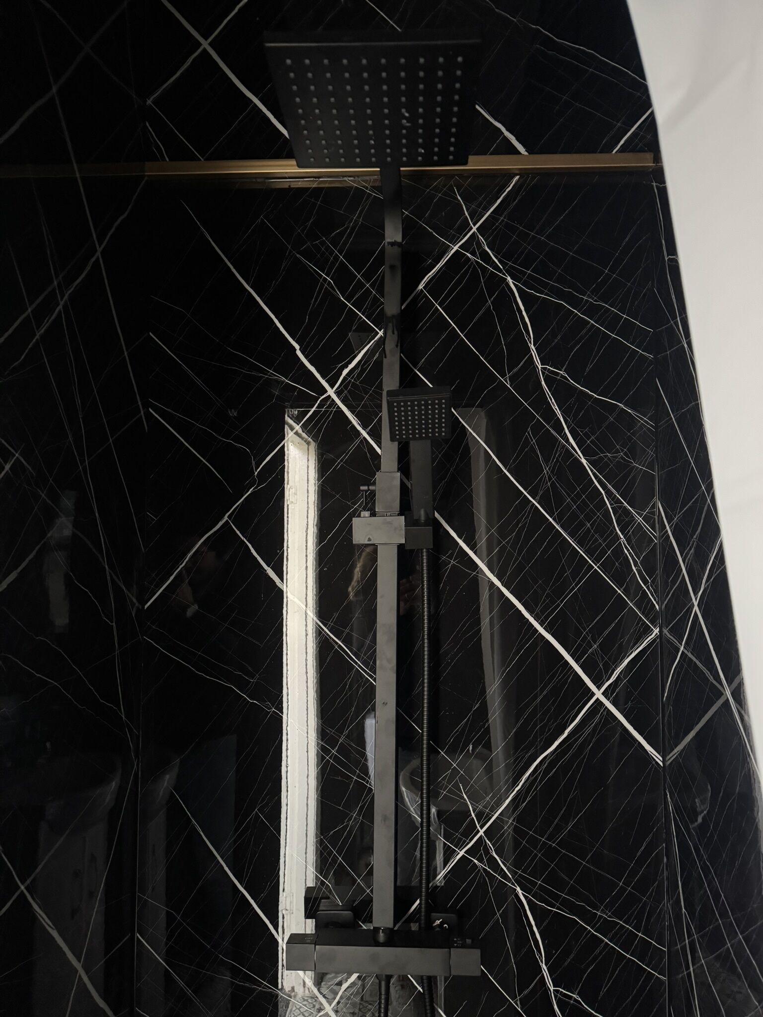 A shower enclosure with a black, cracked glass door and a metal frame.