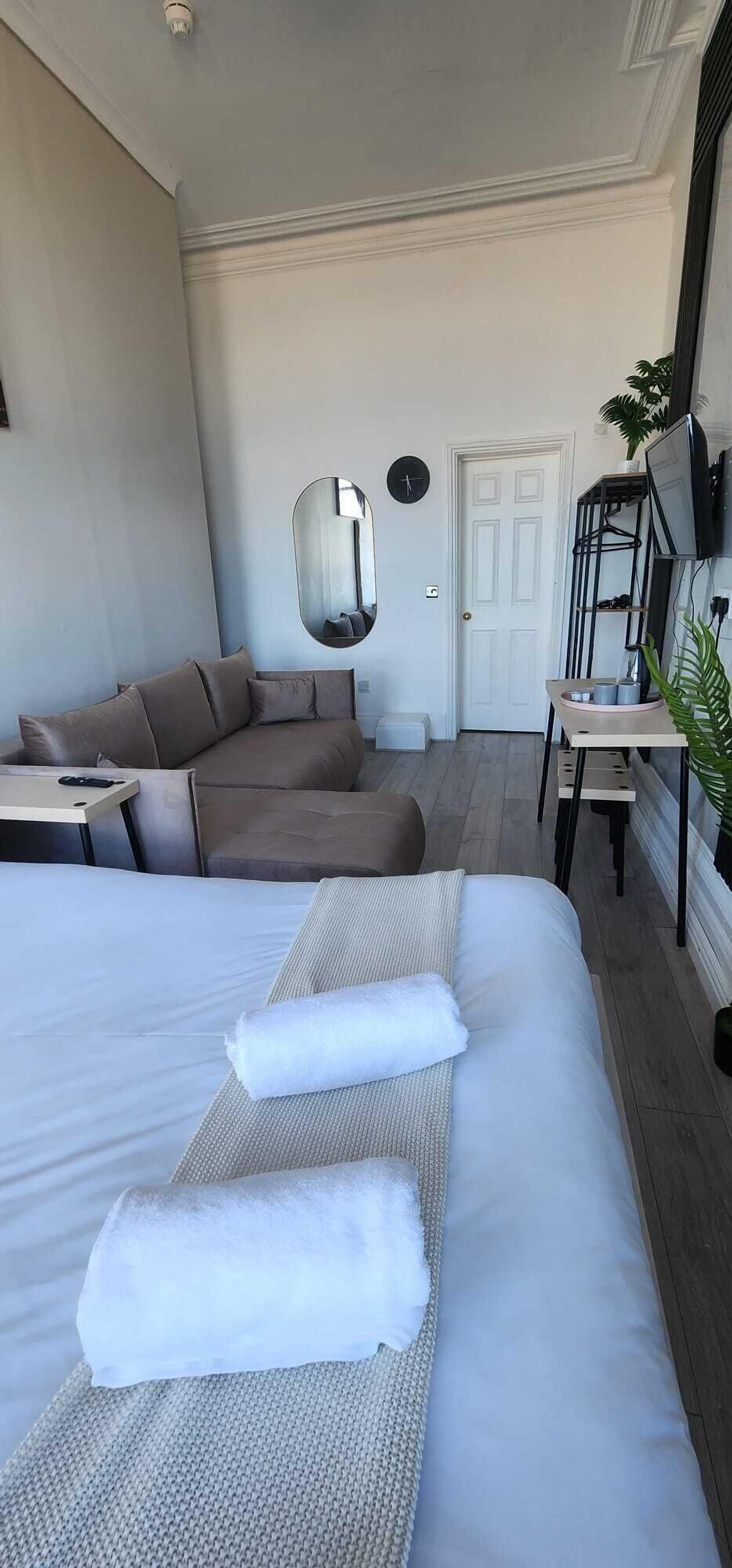 A hotel room with two beds, a TV, a desk, and a mirror.