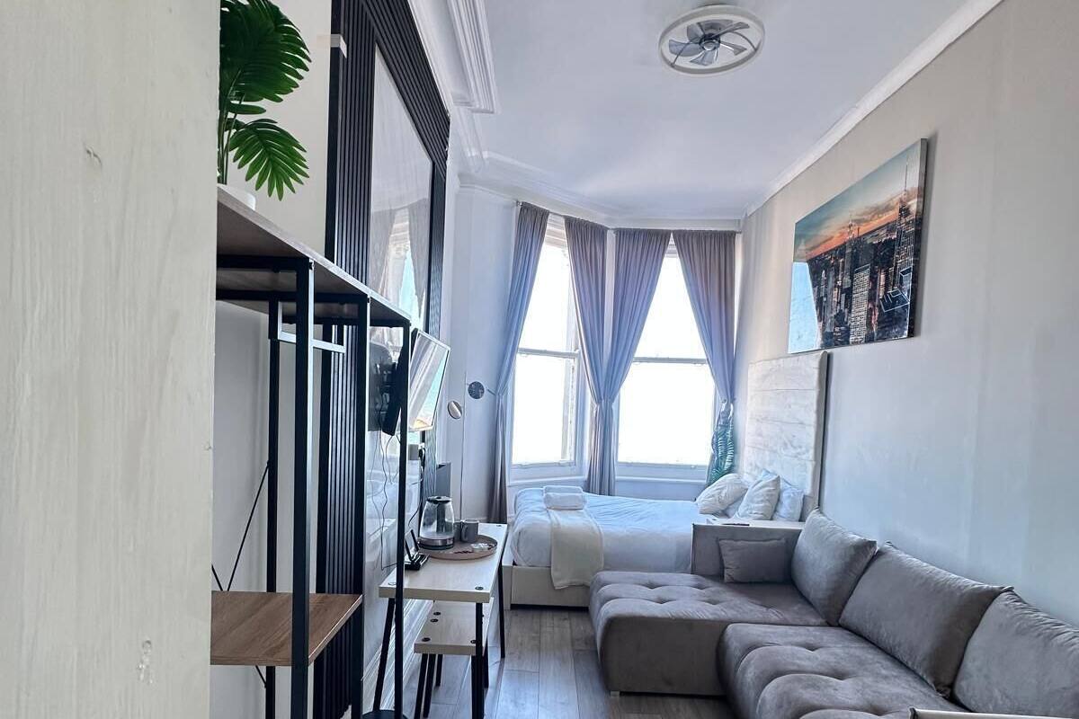 A modern living room with a sofa, a desk, and a bookshelf.