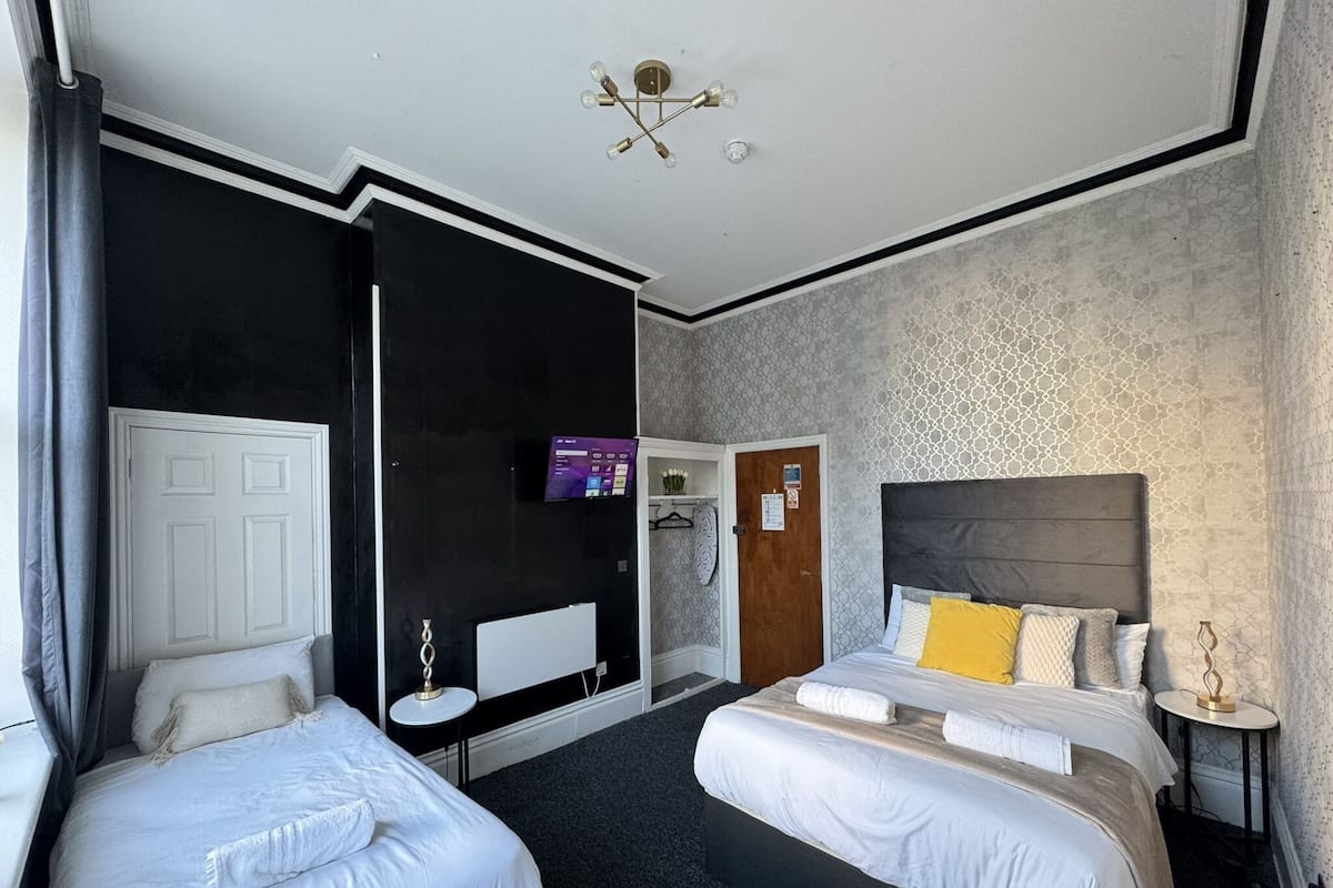A hotel room with two beds, a television, a small table, and a wardrobe.