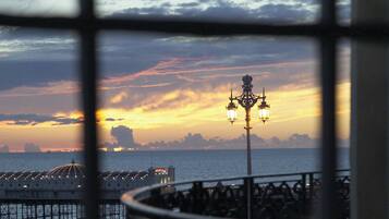 A sunset view through a window with a street lamp and a pier in the background.
