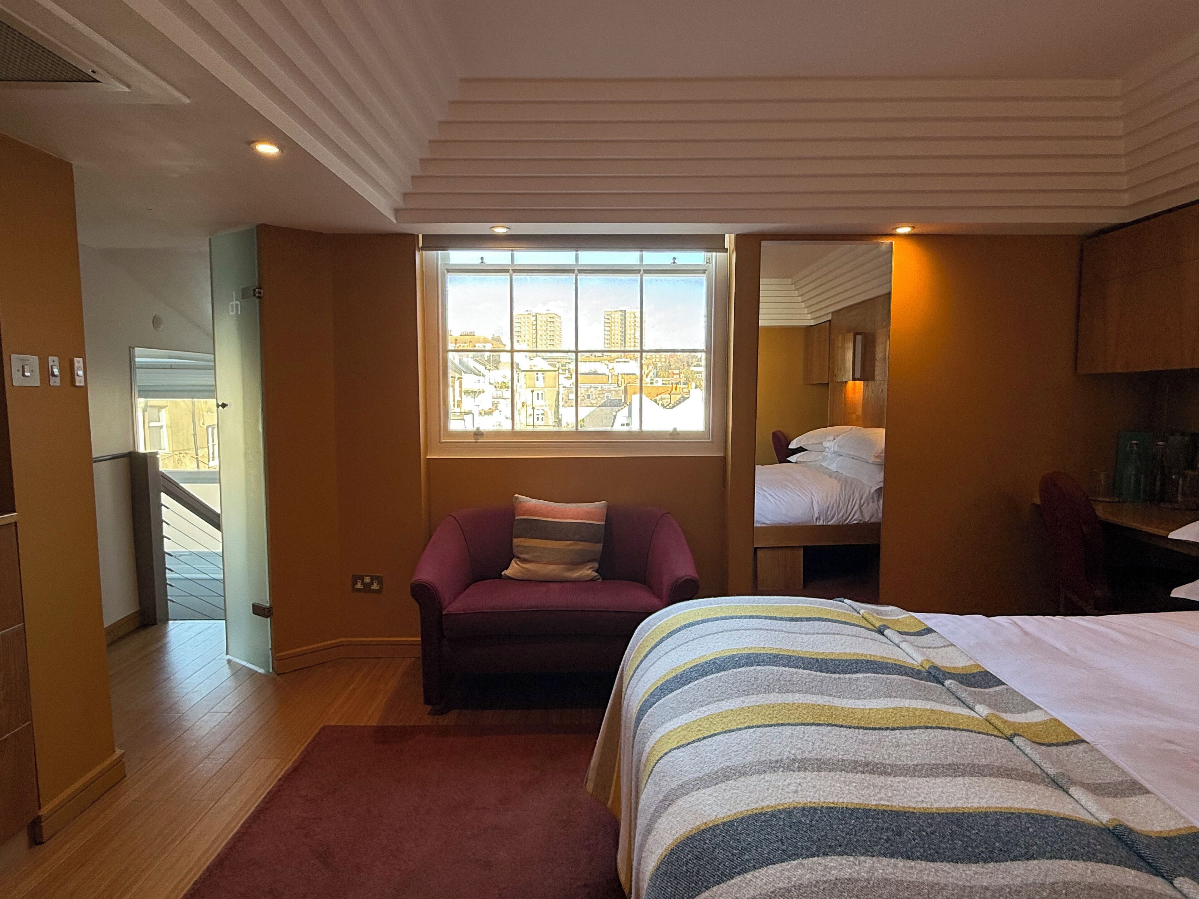 Ett hotellrum med en s äng, ett fönster med utsikt över staden, en soffa och ett skrivbord.