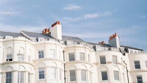 A row of white buildings with multiple chimneys and a clear blue sky. - Drakes of Brighton (Brighton)