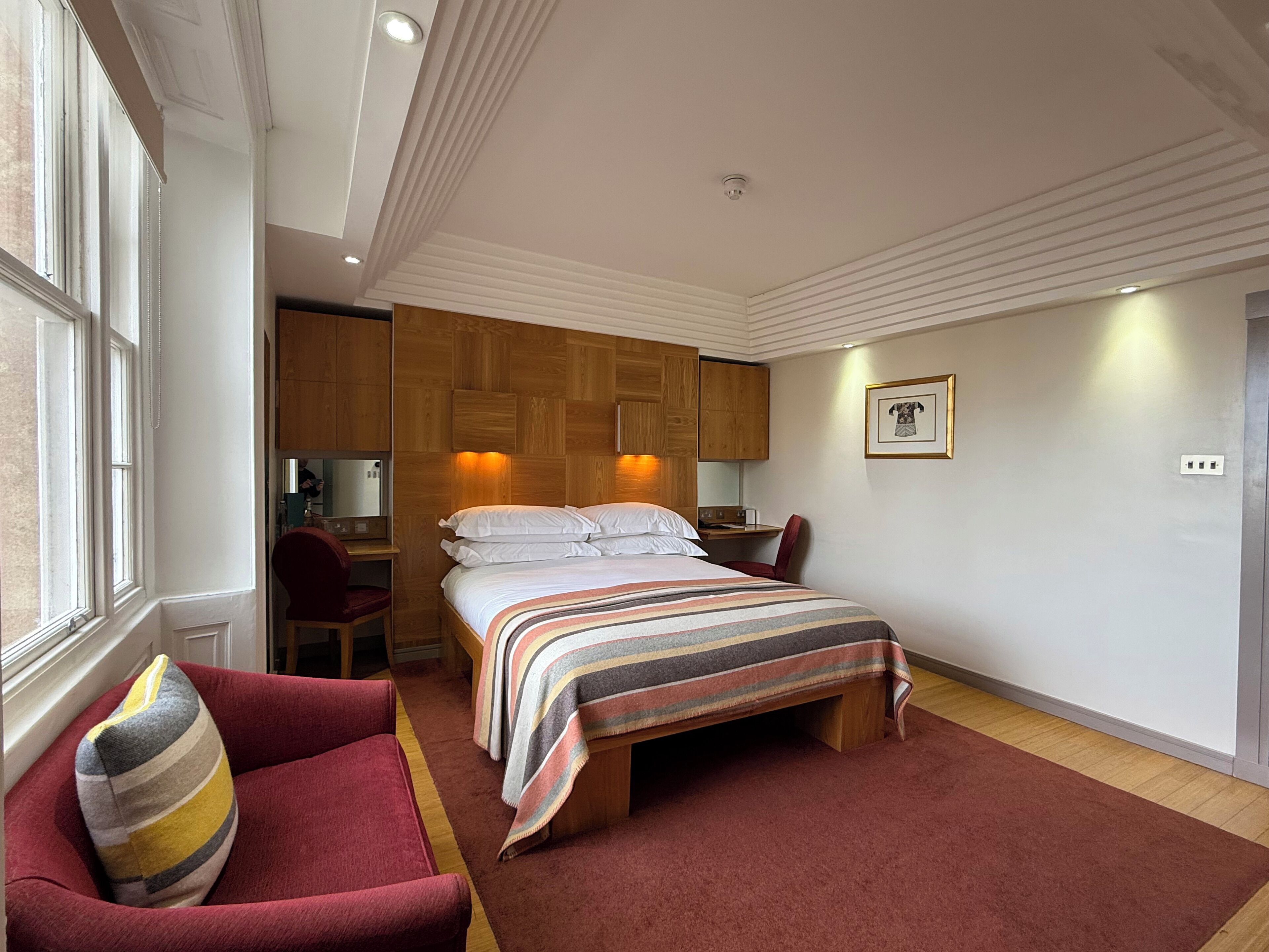 A bedroom with a bed, a desk, a chair, and a window.