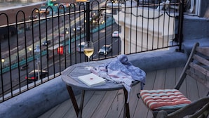 A balcony with a table and two chairs, overlooking a cityscape and a body of water during sunset. - Drakes of Brighton (Brighton)