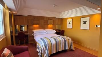Ein Hotelzimmer mit einem Bett, einem Schreibtisch, einem Stuhl und einer kleinen Küchenzeile.