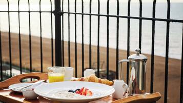A breakfast tray on a wooden table with a view of the beach.