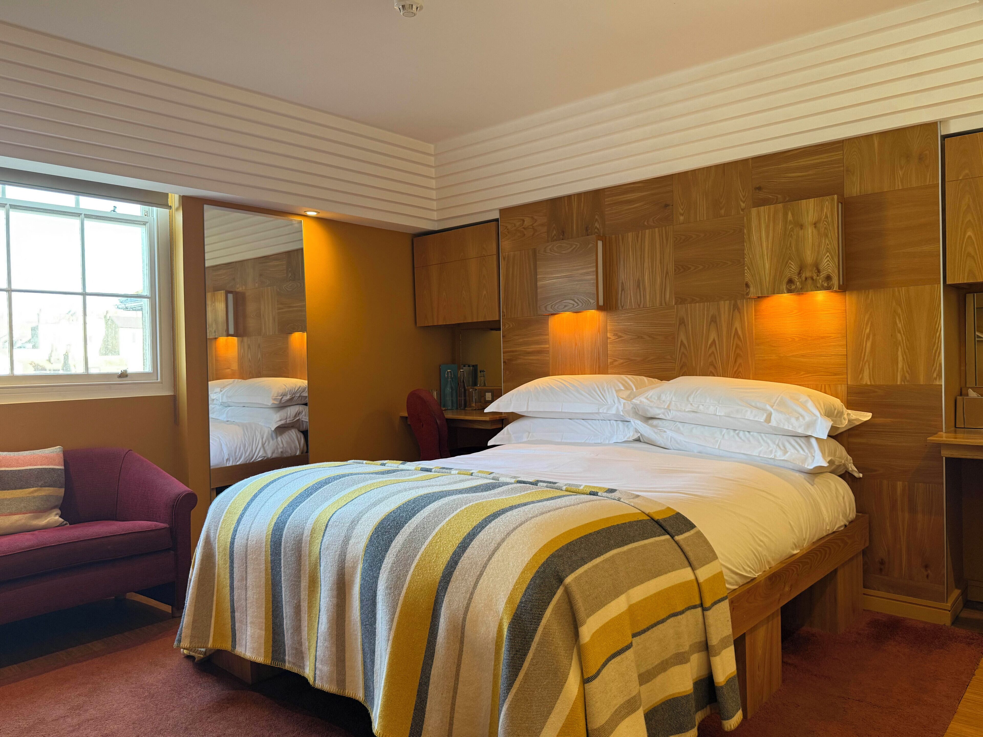 Une chambre d’hôtel avec un grand lit, un petit bureau, une chaise et une fenêtre.