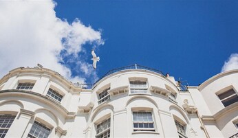 A white building with multiple windows and balconies, under a clear blue sky.
