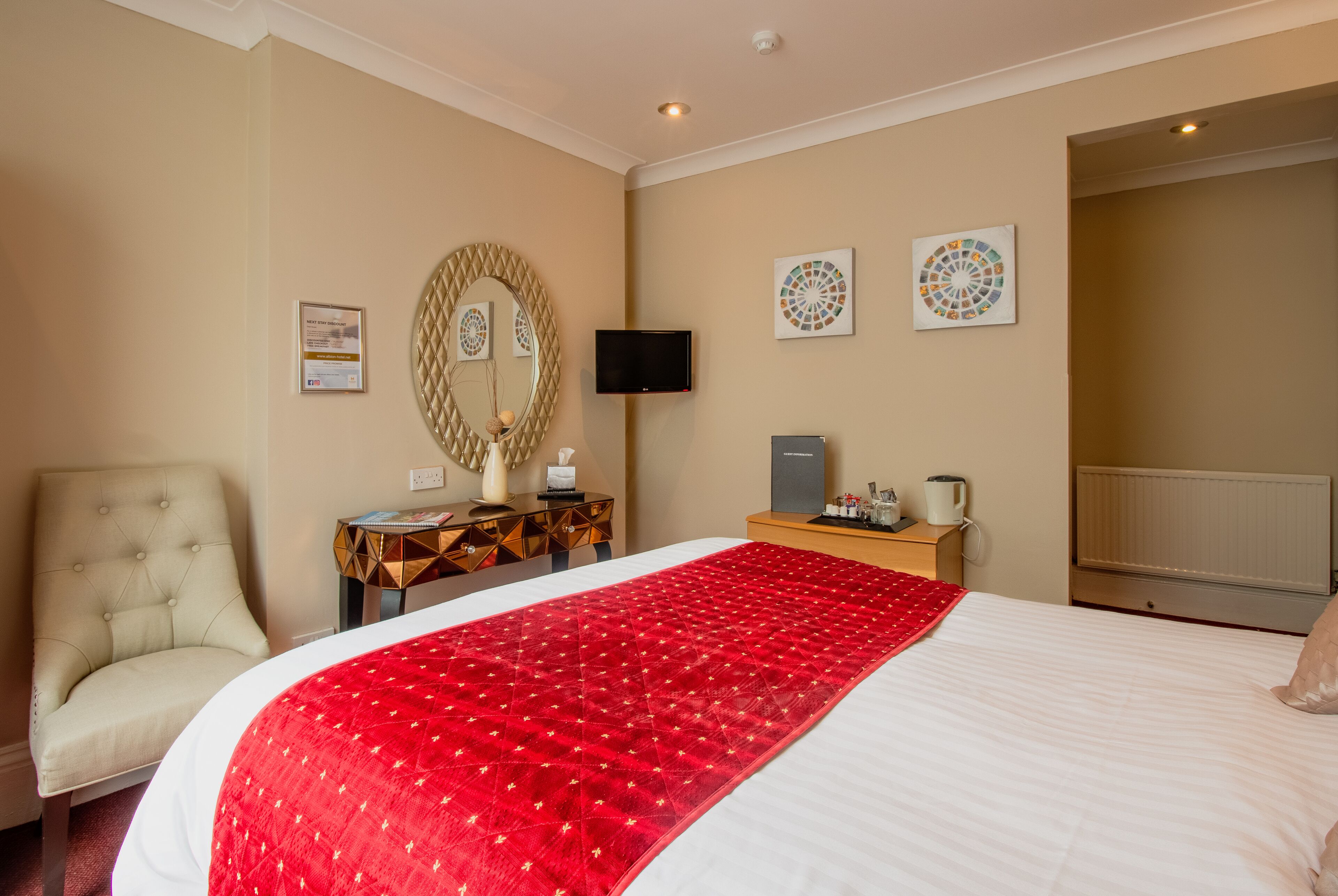 A hotel room with a large bed, a chair, a TV, and a small table with a coffee maker.