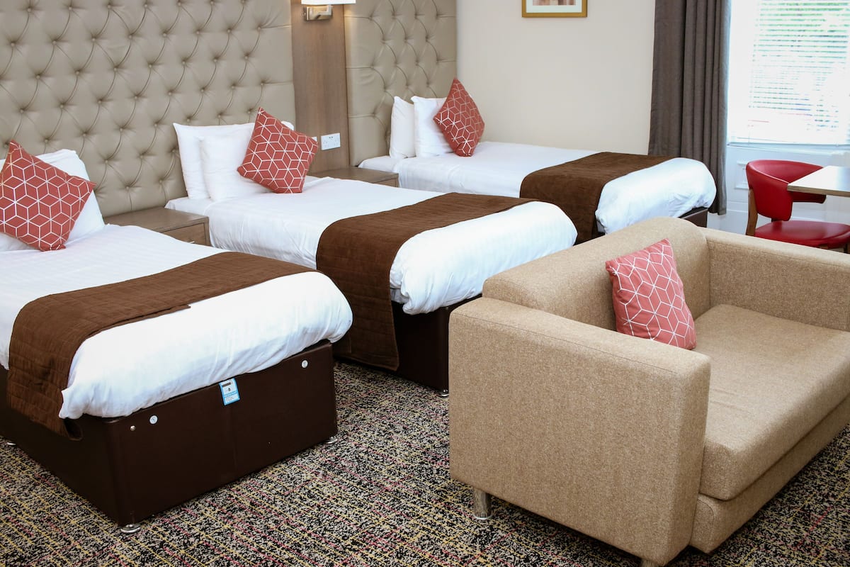 A hotel room with three beds, a sofa, and a small table.