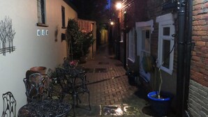 A narrow alleyway with brick walls, a metal table and chairs, and a blue pot on the ground. - Newport Quay Bed and Breakfast (Newport)