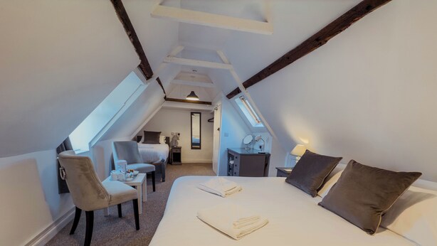 A bedroom with a large bed, a desk, a chair, and a small table with a lamp. There is a window and a mirror on the wall. - Newport Quay Bed and Breakfast (Newport)