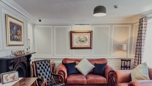 A living room with a fireplace, leather sofas, a wooden table, and framed artwork on the walls. - Newport Quay Bed and Breakfast (Newport)