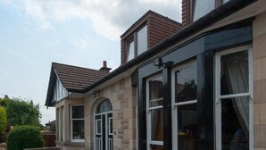 A patio area with outdoor seating and a stone building with large windows. - Boreland Lodge Hotel (Dunfermline)