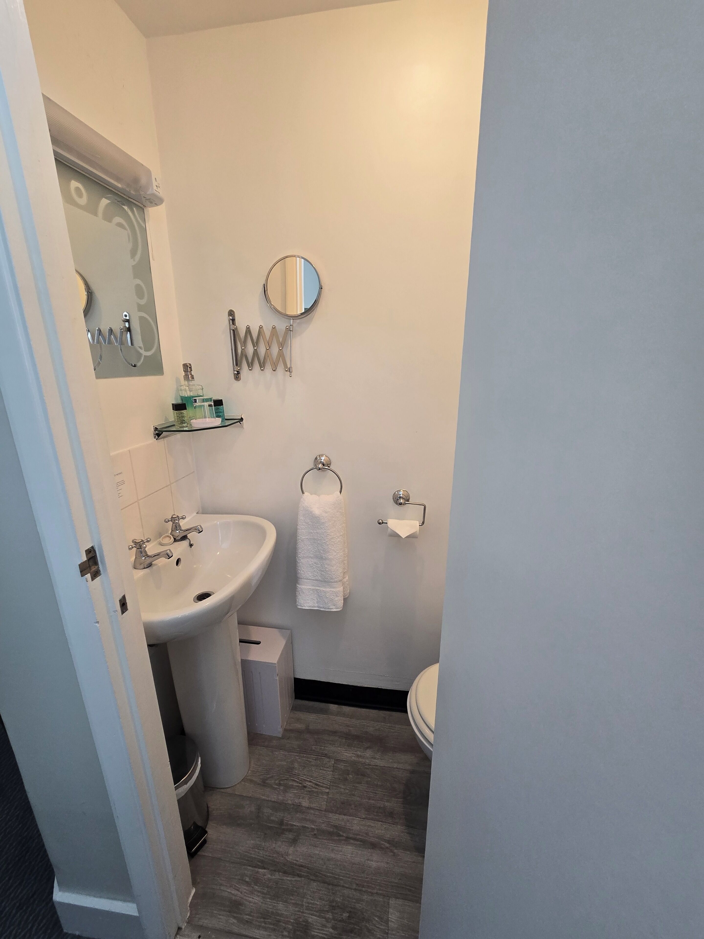 Un baño con lavamanos, espejo, toallero y retrete.